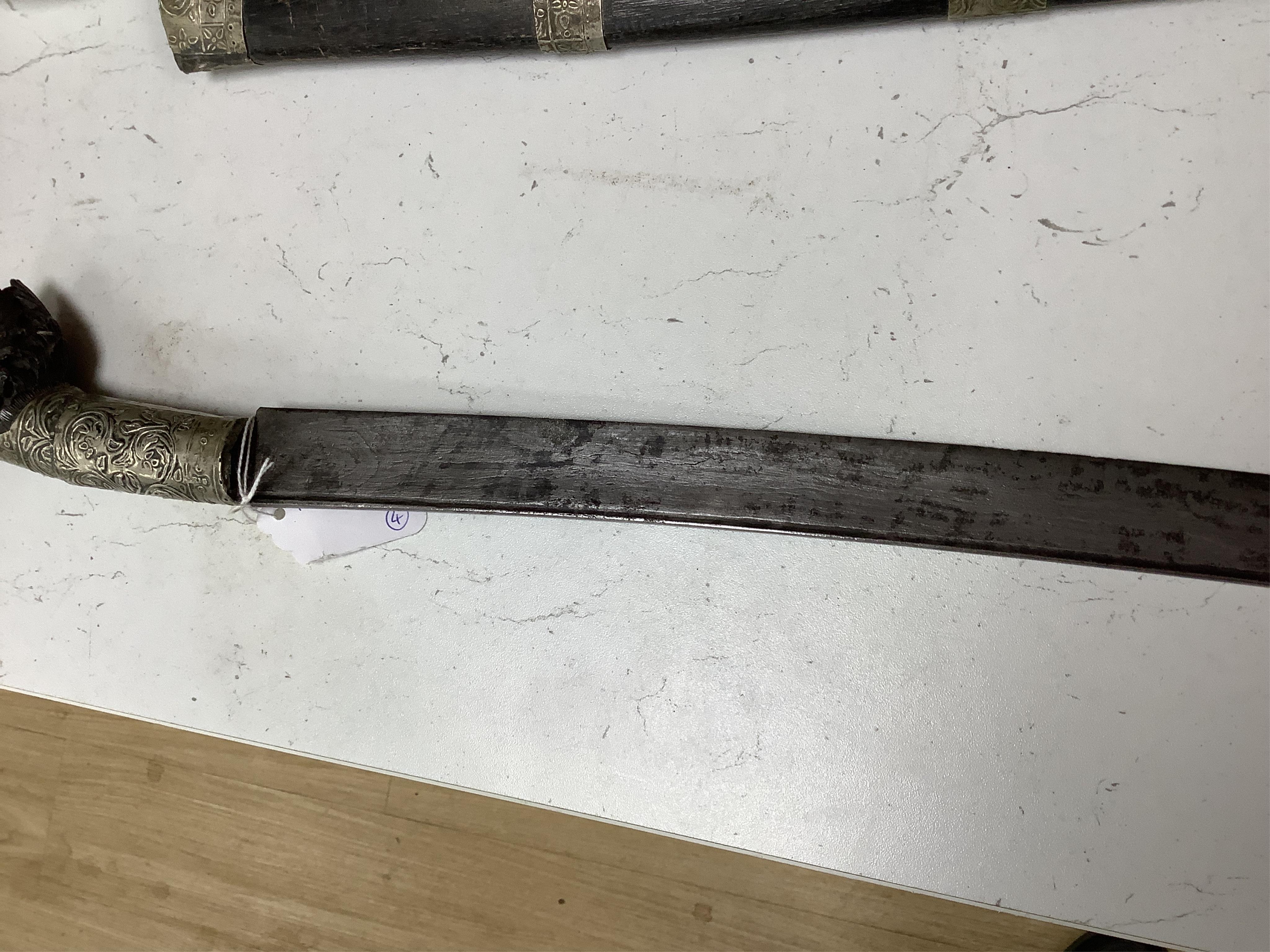 Four bladed weapons; an Indian sword Tulwar, blade 68.5cm. Condition - poor, heavily pitted., A Nepalese Kukri. Condition - fair., A Thai sword Dha, with a lacquered hilt and wooden scabbard, blade 56cm. Condition - fair